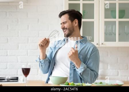 Funny guy singing holding microphone du batteur dans la cuisine cuisine moderne Banque D'Images
