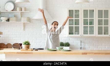 Heureux jeune femme lever les mains se sentir excité la cuisson dans la cuisine Banque D'Images