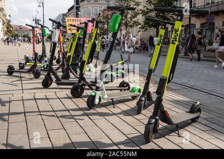 Beaucoup de scooters électriques, escooter ou e-scooter de la ruche d'entreprise partage ride sur un trottoir de gauche à Varsovie, Pologne Banque D'Images