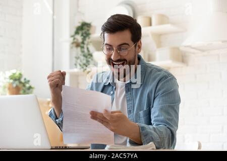L'homme excité la lecture de courrier postal lettre vraiment comblée par de bonnes nouvelles Banque D'Images