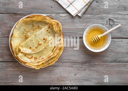 Blinis (crêpes) et de miel sur fond de bois, vue du dessus, copiez l'espace. Crêpes minces faits maison pour le petit-déjeuner ou un dessert. Banque D'Images