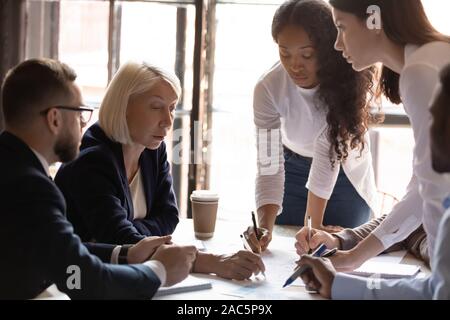 Groupe ciblé de divers jeunes managers à l'écoute du leader remarques. Banque D'Images