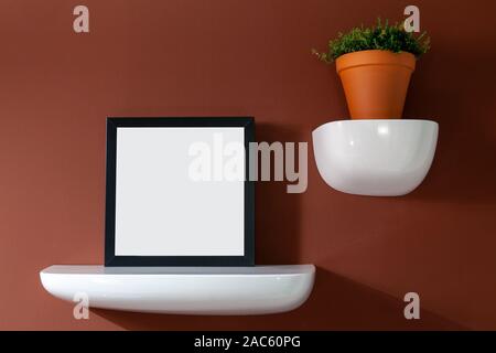 Cadre photo avec un poster sur le mur rouge avec une fleur dans un pot Banque D'Images