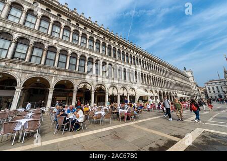 Piazza San Marco, place et anciens bâtiments appelé Procuratie Vecchie. Des groupes de touristes se promener ou s'asseoir au bar en plein air. Vénétie, Italie, Europe Banque D'Images