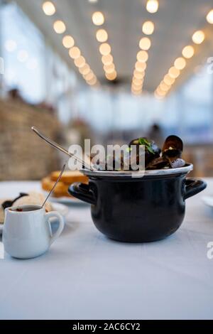 Les moules cuites à la vapeur dans une sauce au vin blanc dans une casserole noir sur la table, du pain , cavier et sauce Banque D'Images