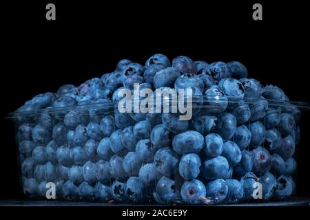 Bleuets frais en plastique réutilisable food pack sur fond noir. Close-up of Bog Bog, myrtille, myrtille myrtille du nord ou l'ouest blueberry Banque D'Images