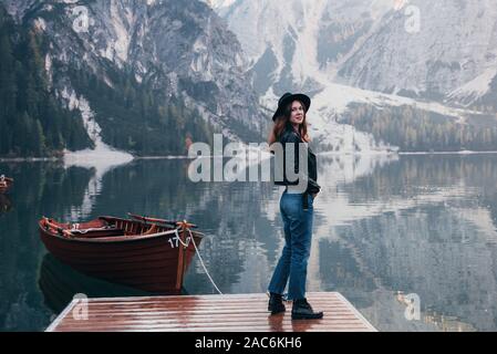 Côté fille est sous tension. Woman in black hat bénéficiant de montagnes près du lac avec bateaux Banque D'Images