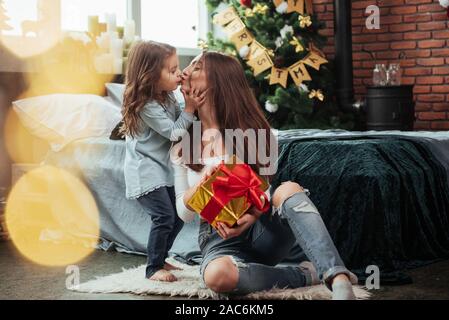 Scène mignon de Kiss. Mère et fille se trouve dans maison de vacances décorée et est titulaire d'gift box Banque D'Images