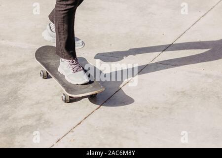 La planche à roulettes. Jambes en jeans et baskets sur planche. Banque D'Images