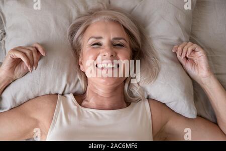 Heureux jour femmes âgées Lying in Bed looking at camera Banque D'Images