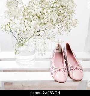 Bouquet de gypsophile dans un vase de verre transparent et rose chaussures de la mariée sur une étagère sur une étagère Banque D'Images
