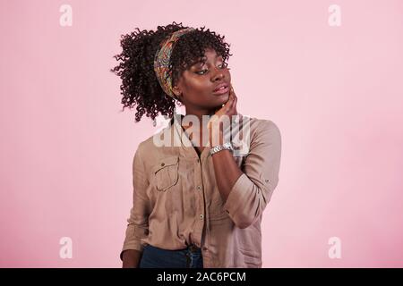 Portrait of attractive african american girl dans des vêtements décontractés et regardez sous la main posant pour l'appareil photo Banque D'Images