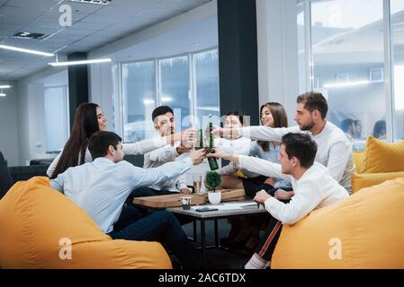 La célébration de traiter avec succès. Les jeunes travailleurs de bureau assis près de la table avec de l'alcool Banque D'Images