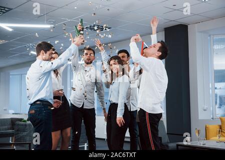 Tout le monde est heureux. Photo de jeune équipe en vêtements classiques Célébrons les succès tout en maintenant des boissons dans le bon bureau moderne éclairé Banque D'Images