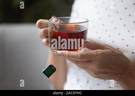 Vue rapprochée des femmes âgées hands holding cup avec le thé noir Banque D'Images