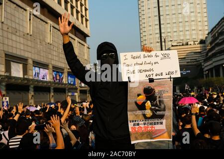 Un manifestant vêtu de noir fait un geste tout en tenant une pancarte lors de la démonstration.Manifestations à Hong Kong continuent comme les groupes pro-démocratiques a remporté l'élection du conseil de district récemment. Les manifestants continuent de demander que le gouvernement de Hong Kong pour répondre à leurs demandes. 5 Banque D'Images