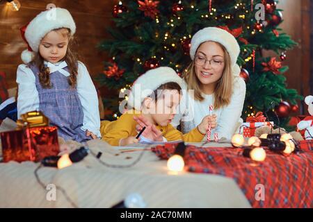 Maman avec enfants attire dans la pièce avec l'arbre de Noël. Banque D'Images