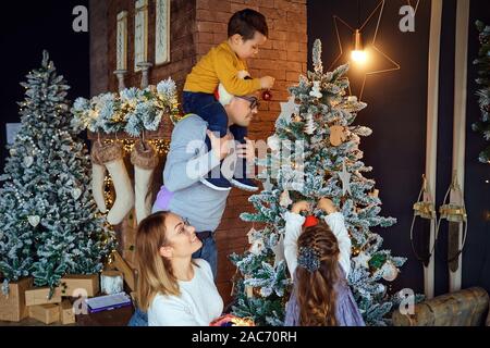 Parents et enfants decorating Christmas Tree Banque D'Images