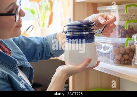 Femme dans la cuisine avec de la menthe sèche peut, le stockage des aliments, garde-manger. Banque D'Images