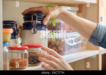 Femme dans la cuisine avec de la menthe sèche peut, le stockage des aliments, garde-manger. Banque D'Images