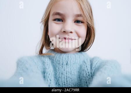 Portrait d'une petite fille dans un pull bleu sur fond blanc Banque D'Images