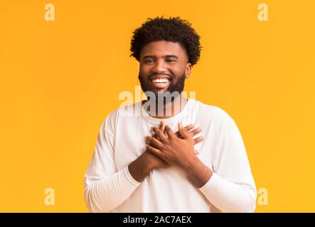 Smiling african man en plaçant les mains à côté de coeur Banque D'Images