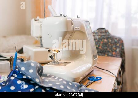 Tissu, matériel de couture et une machine à coudre sur une table dans une chambre Banque D'Images