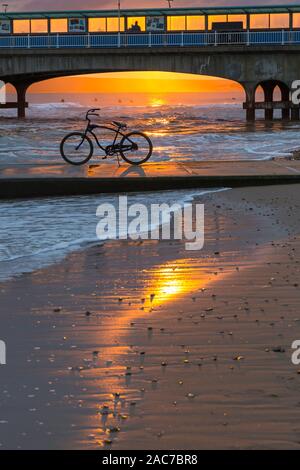 Bournemouth, Dorset UK. 1er décembre 2019. Météo France : magnifique coucher de soleil à la plage de Bournemouth à la fin d'un froid glacial d'hiver ensoleillé sec 24. Vélo, vélo, sur le bord de la mer qui se profile dans le coucher du soleil encadré par la jetée. Credit : Carolyn Jenkins/Alamy Live News Banque D'Images