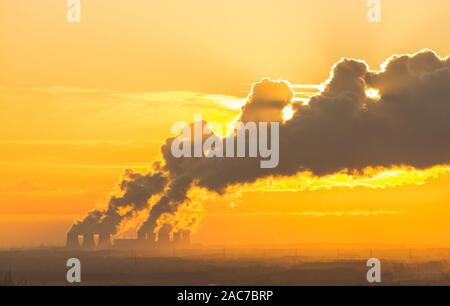 Soleil derrière la piste d'une vapeur d'eau de la station d'alimentation des tours de refroidissement sur une froide nuit d'hiver. Une vue lointaine de la centrale électrique près de Drax Banque D'Images