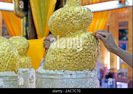 Homme plaçant une feuille d'or sur la statue de Bouddha dans la Pagode Phaung Daw Oo. Lac Inle Myanmar Birmanie Banque D'Images