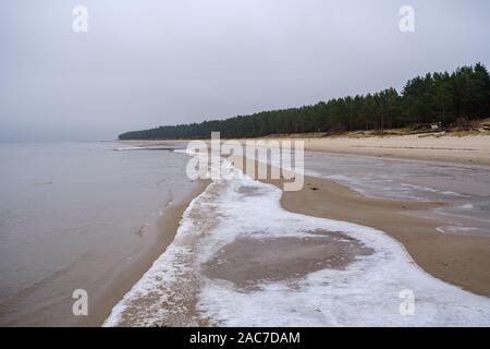 Plage de la mer congelés avec du sable et de la neige en premier jour nuageux en hiver Banque D'Images