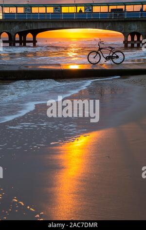 Bournemouth, Dorset UK. 1er décembre 2019. Météo France : magnifique coucher de soleil à la plage de Bournemouth à la fin d'un froid glacial d'hiver ensoleillé sec 24. Vélo, vélo, sur le bord de la mer qui se profile dans le coucher du soleil encadré par la jetée. Credit : Carolyn Jenkins/Alamy Live News Banque D'Images