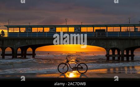 Bournemouth, Dorset UK. 1er décembre 2019. Météo France : magnifique coucher de soleil à la plage de Bournemouth à la fin d'un froid glacial d'hiver ensoleillé sec 24. Vélo, vélo, sur le bord de la mer qui se profile dans le coucher du soleil encadré par la jetée. Credit : Carolyn Jenkins/Alamy Live News Banque D'Images