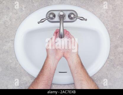 L'homme se laver les mains dans la salle de bains lavabo. Vue du haut vers le bas. Banque D'Images