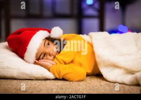 Peu d'african girl prétendant dormir, en attente de Santa sur plancher Banque D'Images