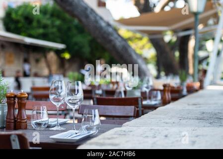 Mis à table avec des couverts et verres à vin sur la terrasse d'un restaurant sur le mur de la ville de la vieille ville de Korčula, Dalmatie du Sud, Croatie Banque D'Images