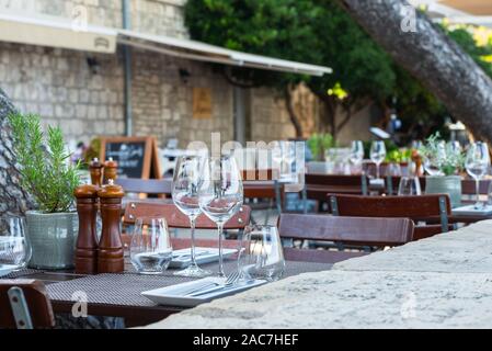 Mis à table avec des couverts et verres à vin sur la terrasse d'un restaurant sur le mur de la ville de la vieille ville de Korčula, Dalmatie du Sud, Croatie Banque D'Images