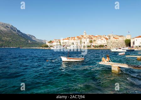 Woman in bikini with soleil devant le panorama de la vieille ville de Korčula dans le soleil du soir, l'île de Korčula, Dalmatie du Sud, Croatie Banque D'Images