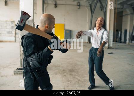 L'homme militaire avec ax, zombie en usine abandonnée Banque D'Images