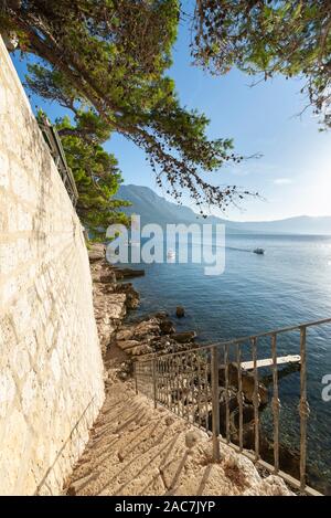 Escaliers vers le bas aux rochers sur l'eau en dessous de la muraille de la ville de Korcula avec vue sur la mer et les montagnes de Peljesac, Dalmatie, Croatie Banque D'Images