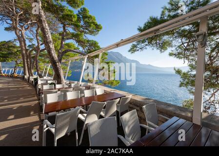 Des tables et des chaises vides sur la terrasse des restaurants sur la muraille de la vieille ville de Korčula dans le soleil du matin, l'île de Korcula, Croatie Banque D'Images