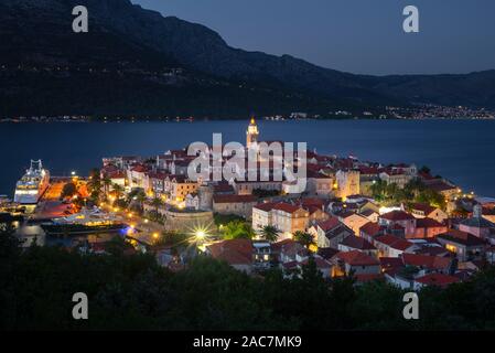 Vue sur les rues médiévales et les bâtiments de la vieille ville historique de Korcula en face de l'île de Peljesac après le coucher du soleil dans l'heure bleue Banque D'Images