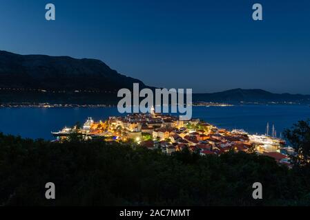 Vue sur les rues médiévales et les bâtiments de la vieille ville historique de Korcula en face de l'île de Peljesac après le coucher du soleil dans l'heure bleue Banque D'Images