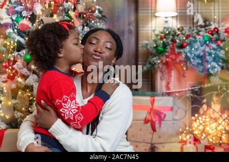 Maman et sa fille afro aimant baiser, féliciter avec Noël Banque D'Images