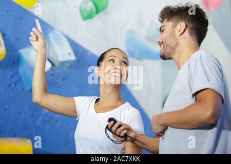 Avec l'instructeur sportif par un mur d'escalade intérieur Banque D'Images