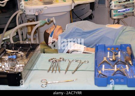 opération simulée montrant un patient (manakin) et une machine anesthésique en arrière-plan et des instruments chirurgicaux en premier plan Banque D'Images