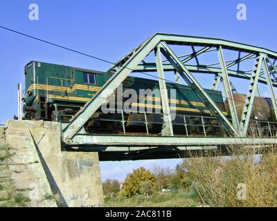 Zrenjanin, Serbie, 28 octobre 2009. Une locomotive tirant un train entre un pont sur la rivière. Banque D'Images