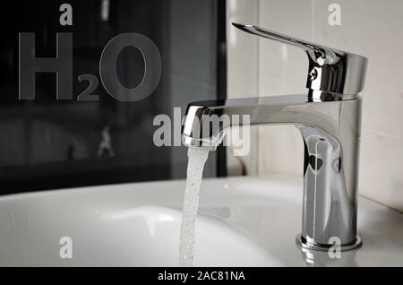 L'eau coule du robinet ou robinet de salle de bains. H2O written Banque D'Images