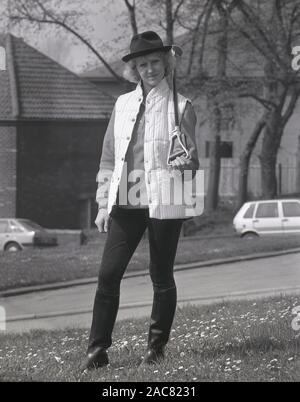 Années 1980, historiques, une dame avec un bâton de prise de certains des derniers modèles British countrywear, England, UK. Banque D'Images