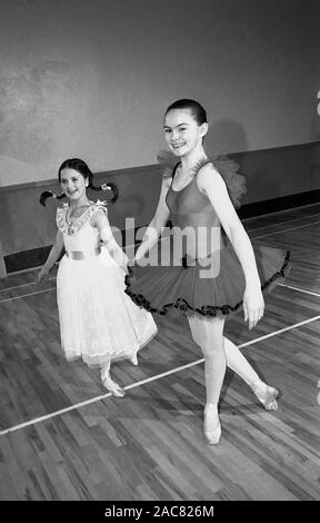 Années 1980, historiques, deux jeunes filles dansant à l'intérieur d'une salle d'école, à la fois en costumes de ballet, l'un vêtu d'un tutu avec camisole de danseur, England, UK. Banque D'Images